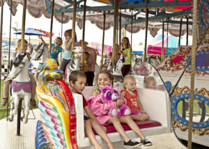 Group of young kids riding carousel ride at Cranberry Blossom Festival