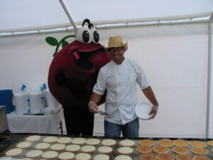 Cranberry Guy mascot and man near pancake griddle